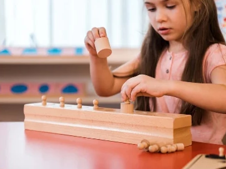 Une élève encastre les cylindres d'un bloc en bois